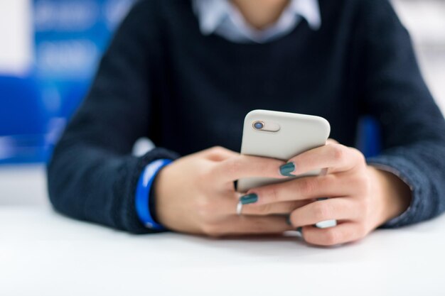 joven estudiante que usa un teléfono móvil durante el descanso en el aula