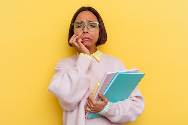 Joven estudiante de raza mixta mujer aislada sobre fondo amarillo