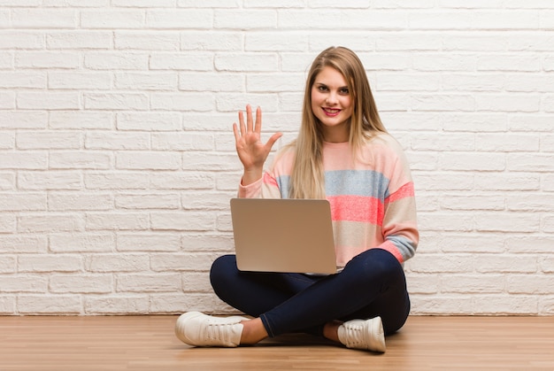 Joven estudiante rusa mujer sentada mostrando el número cinco