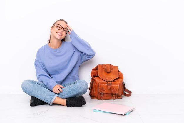 Una joven estudiante sentada en el suelo aislada de fondo blanco se ha dado cuenta de algo y tiene la intención de encontrar la solución