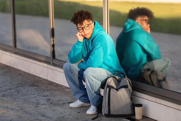 Un joven estudiante sentado afuera con un reflejo