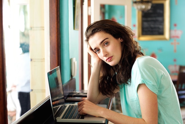 joven estudiante sentado en el café con la computadora portátil