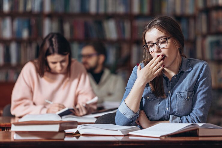 Joven estudiante se siente cansado en la biblioteca universitaria