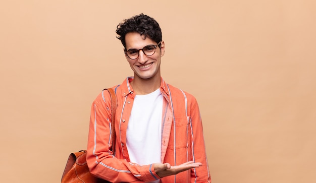 Joven estudiante sonriendo alegremente, sintiéndose feliz y mostrando un concepto en el espacio de la copia con la palma de la mano