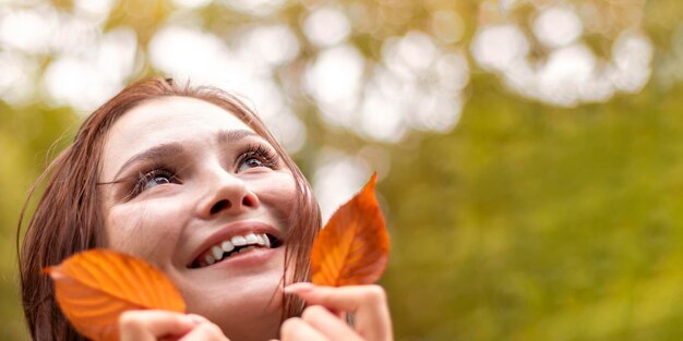 Una joven estudiante sonriendo descuidadamente y disfrutando de un cálido día de otoño en el parque Espacio libre