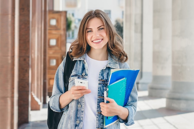 Joven estudiante sonriente contra la universidad.