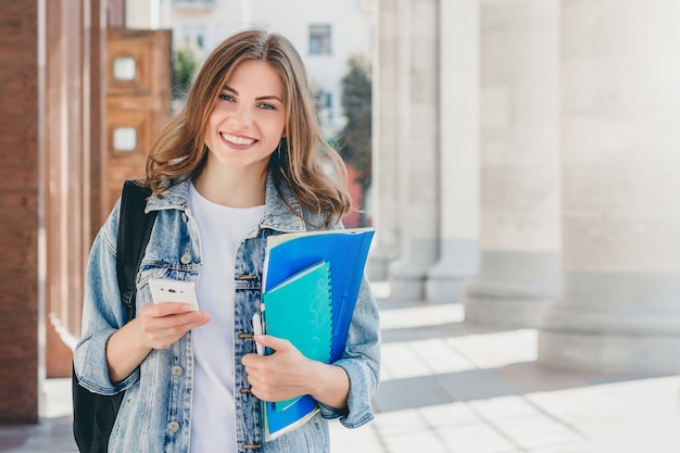 Joven estudiante sonriente contra la universidad.