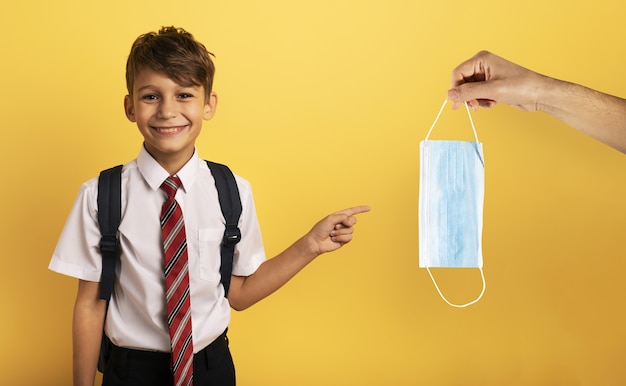 Joven estudiante sonriente indica una mascarilla para covid19.