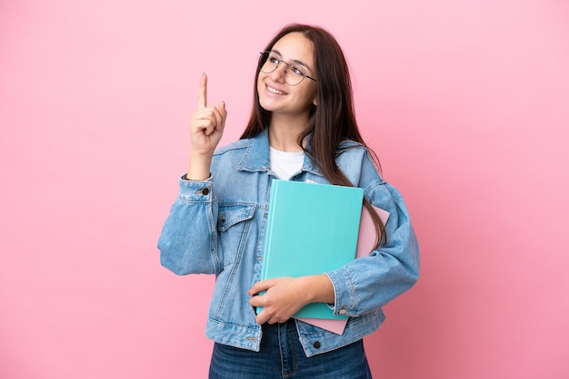 Joven estudiante ucraniana aislada de fondo rosa señalando una gran idea