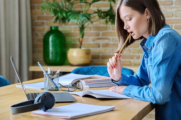 Una joven estudiante universitaria estudiando en casa usando una computadora portátil