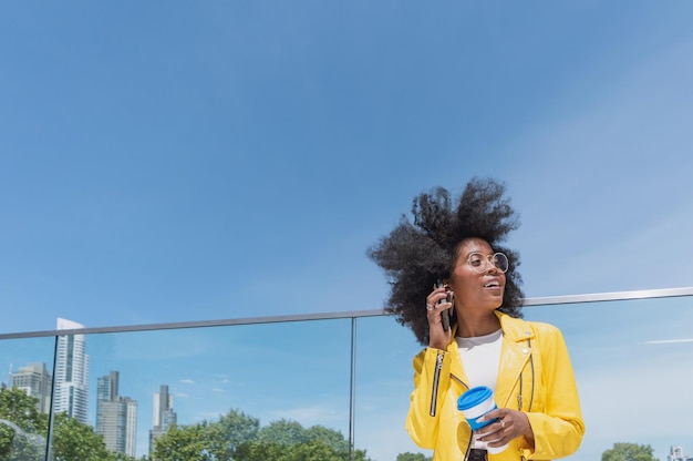 joven estudiante universitaria latina hispana negra con afro al aire libre hablando por teléfono en su descanso tim