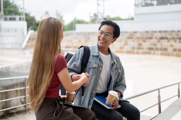 Un joven estudiante universitario asiático feliz y inteligente está estrechando la mano de su amiga