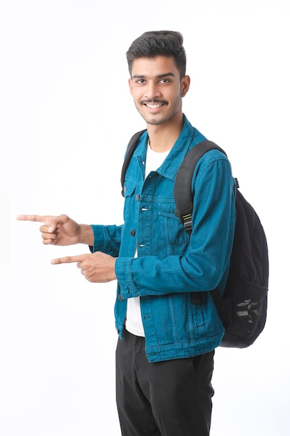 Joven estudiante universitario indio dando expresión sobre fondo blanco.