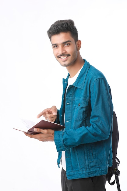 Foto joven estudiante universitario indio con lácteos en la mano sobre fondo blanco.