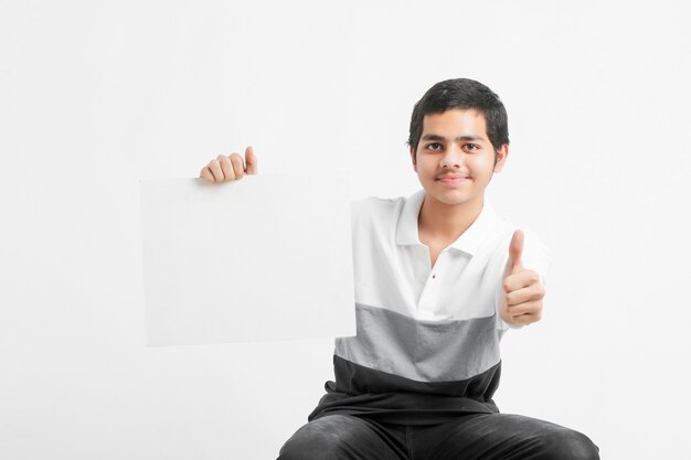 Joven estudiante universitario indio mostrando pizarra en la pared blanca