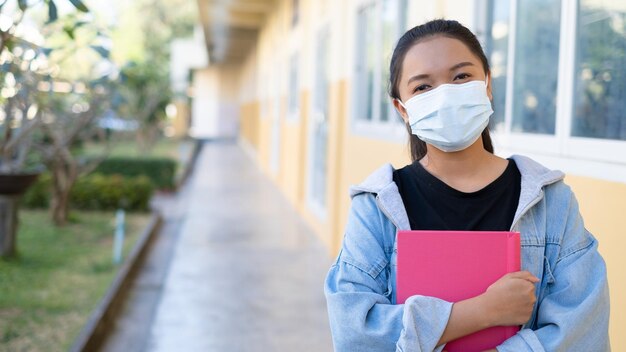 Una joven estudiante usa una máscara caminando en la escuela.