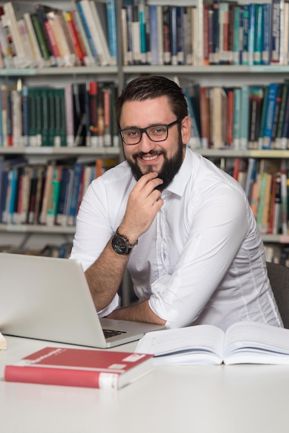 Joven estudiante usando su computadora portátil en una biblioteca