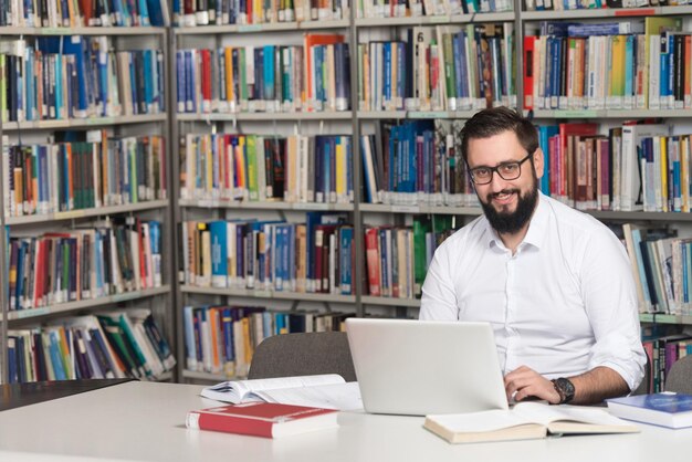 Joven estudiante usando su computadora portátil en una biblioteca