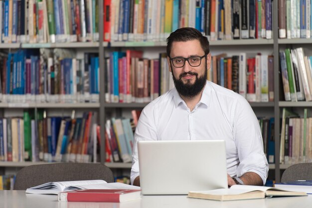 Joven estudiante usando su computadora portátil en una biblioteca