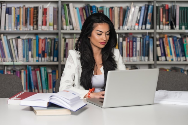 Joven estudiante usando su computadora portátil en una biblioteca