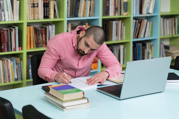 Foto joven estudiante usando su computadora portátil en una biblioteca