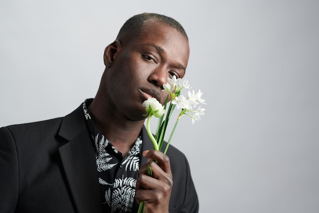 Joven de etnia africana sosteniendo flores blancas junto a su rostro