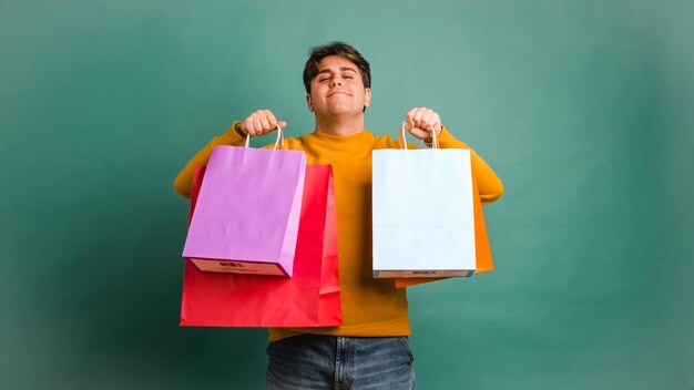 Foto un joven étnico feliz mostrando bolsas de compras