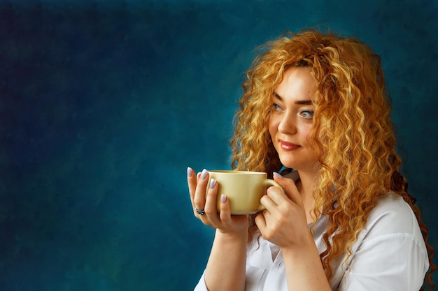 Joven europea bebiendo café por la mañana y sonriendo Cabello largo camisa blanca hora del café