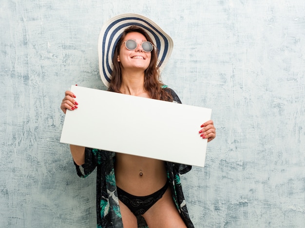 Joven europea vistiendo bikini y sosteniendo una pancarta
