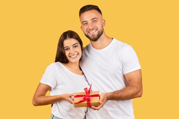 Un joven europeo feliz abraza a su esposa y le da una caja de regalos. Disfruta de las vacaciones, cumpleaños y año nuevo.