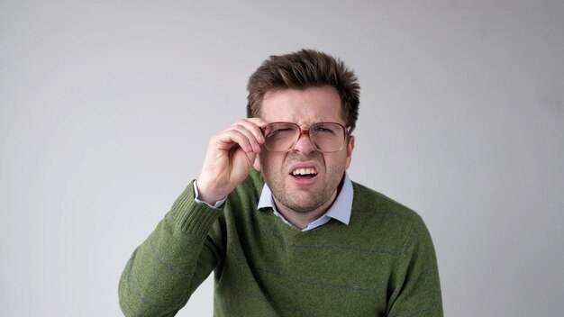 Foto un joven europeo con problemas de visión mira a través de sus gafas tratando de discernir la información que