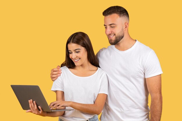 Foto un joven europeo sonriente con una camiseta blanca abrazando a una mujer hablando en la computadora.