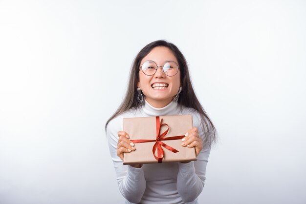 Joven excitada está mostrando un regalo envuelto mientras sonríe a la cámara.