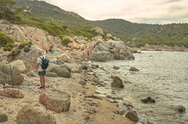 Joven excursionista está visitando un acantilado típico del sur de Cerdeña durante la puesta del sol