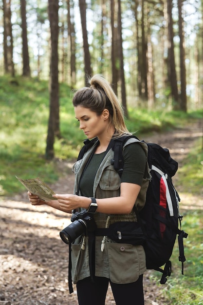 Joven excursionista con mochila grande con mapa para orientación en el bosque