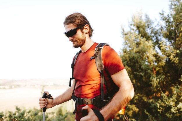 Foto un joven excursionista viaja por las montañas con palos de trekking para la caminata nórdica