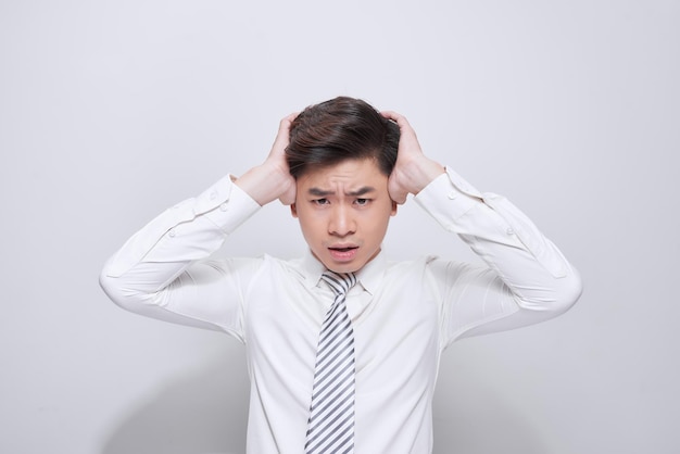 Joven exhausto sosteniendo la cabeza en las manos mientras siente dolor. Chico guapo joven con los ojos cerrados que sufren de dolor de cabeza. Concepto de migraña