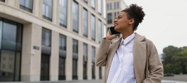 Una joven y exitosa agente de seguros de aspecto afroamericano habla por teléfono móvil