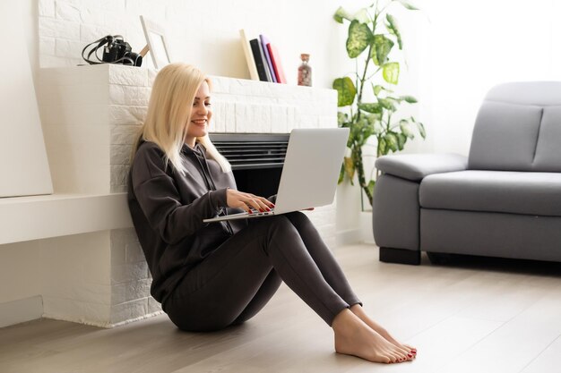 Una joven y exitosa mujer independiente con estilo positivo está trabajando en una computadora portátil. Trabaje desde el apartamento a distancia en línea. Ambiente confortable de oficina en casa. desarrollador de diseño de programador de internet de negocios