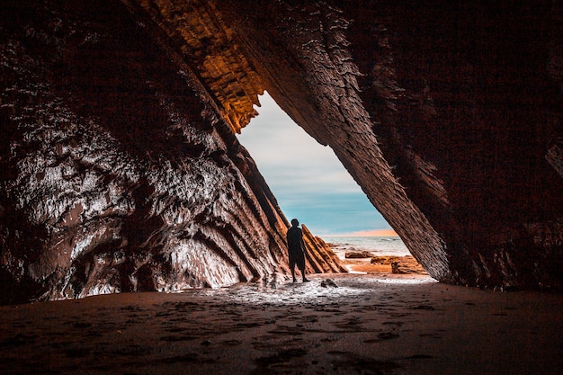 Un joven explora la hermosa cueva natural que se utilizó en el rodaje de Juego de tronos en el flysch de la playa Itzurun en Zumaia. País Vasco...