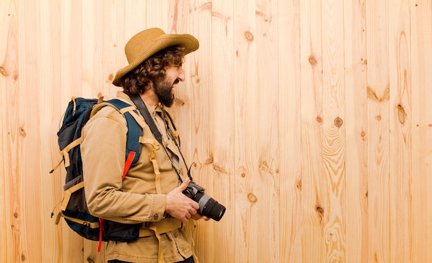 Joven explorador loco con sombrero de paja y mochila en pared de madera