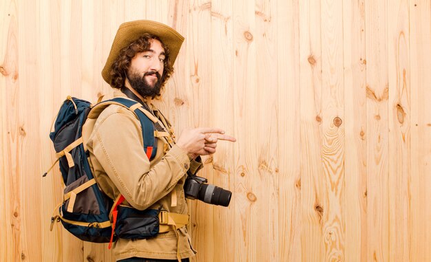 Joven explorador loco con sombrero de paja y mochila en pared de madera