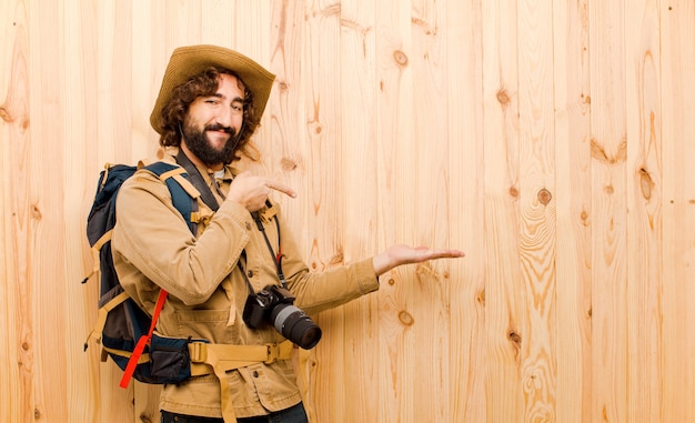 Joven explorador loco con sombrero de paja y mochila en pared de madera