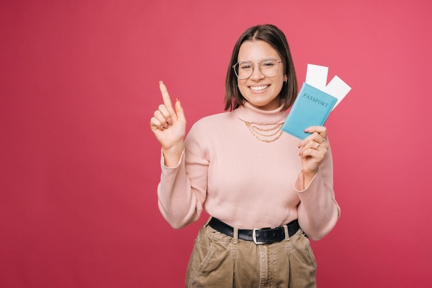 Una joven extasiada sostiene un pasaporte azul mientras señala hacia arriba