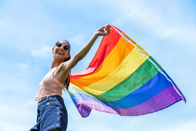 Una joven exuberante agita una vibrante bandera LGBTQ en el aire encarnando el espíritu del Orgullo