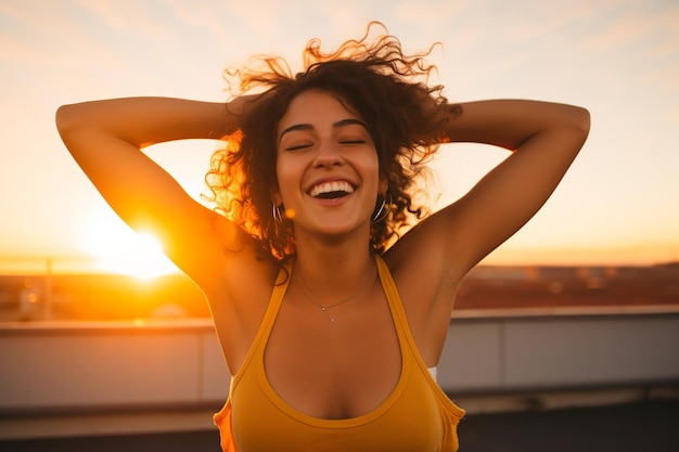 Joven exuberante con una camiseta deportiva contra el fondo naranja del atardecer