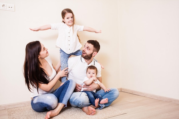 La joven familia de cuatro personas está sentada en el suelo.