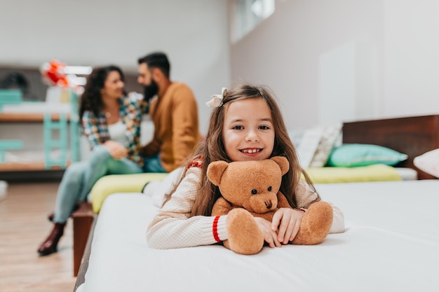 Joven familia feliz comprando cama y colchón nuevos en una gran tienda de muebles