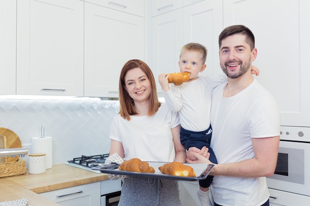 Joven familia feliz con dos hijos jóvenes preparando el desayuno juntos en su cocina