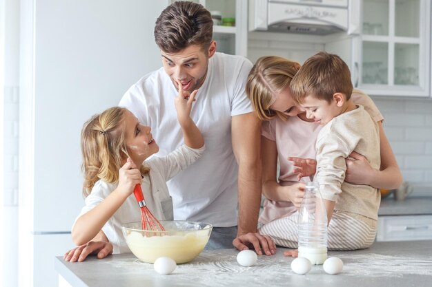 joven familia feliz jugando mientras cocina el desayuno juntos